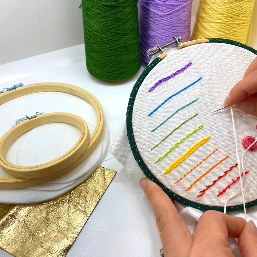 Colorful embroidery stitches in a hoop with spools of thread nearby